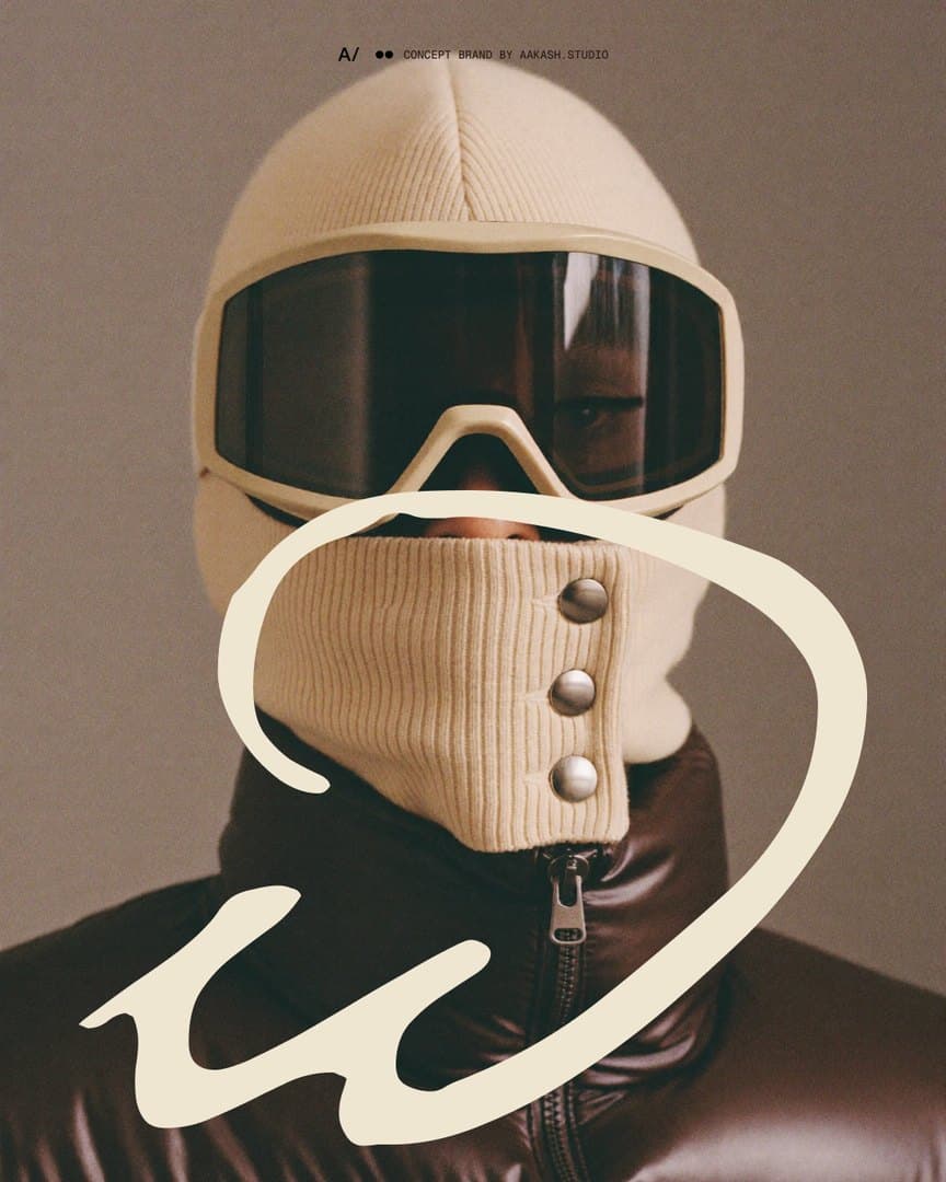 A knit balaclava and goggle in ecru, with the Warm Winters lowercase w drawn large around its snap gaiter