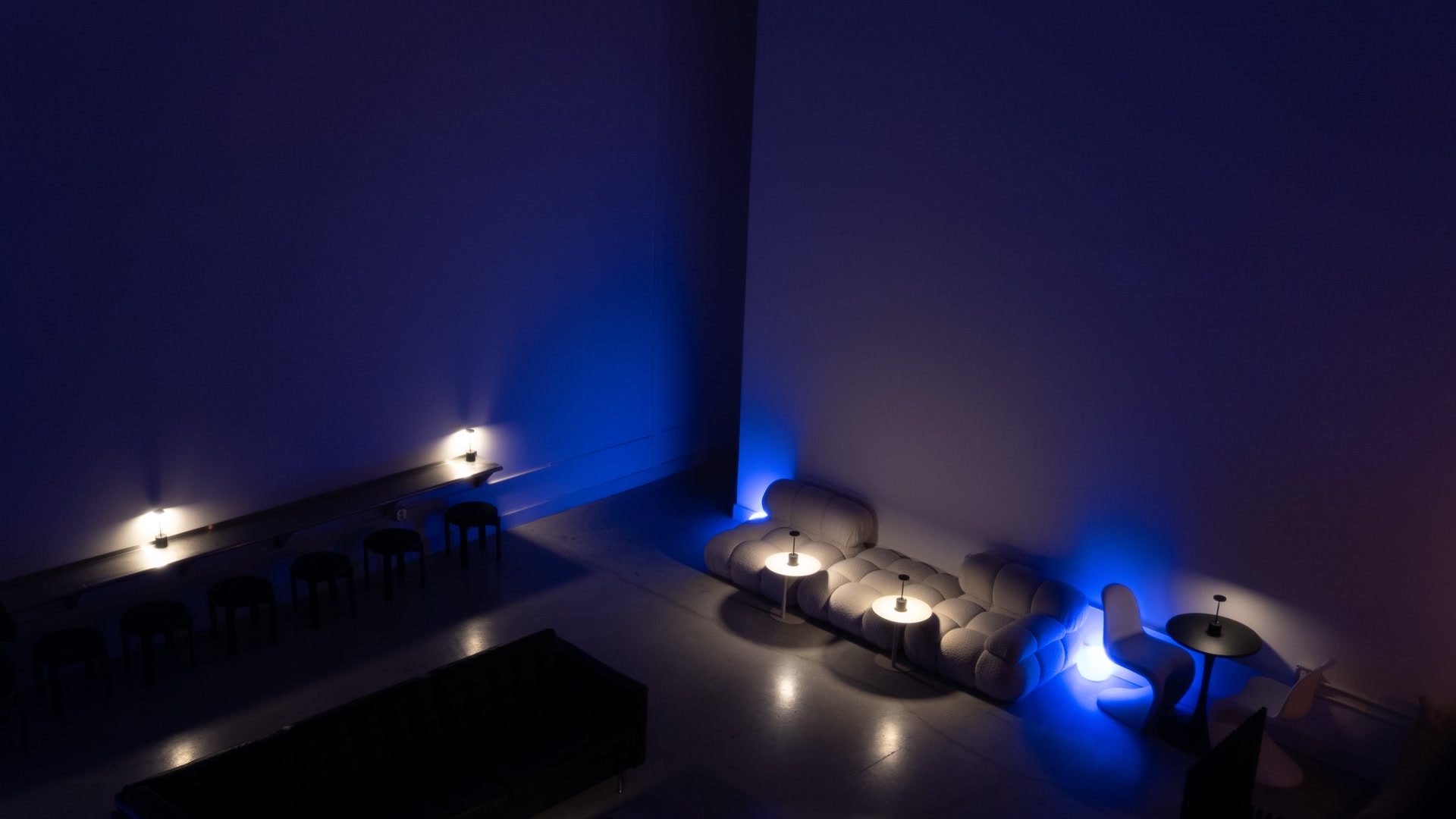 The Safehouse lounge from above, half in cobalt wash and half in warm lamplight.