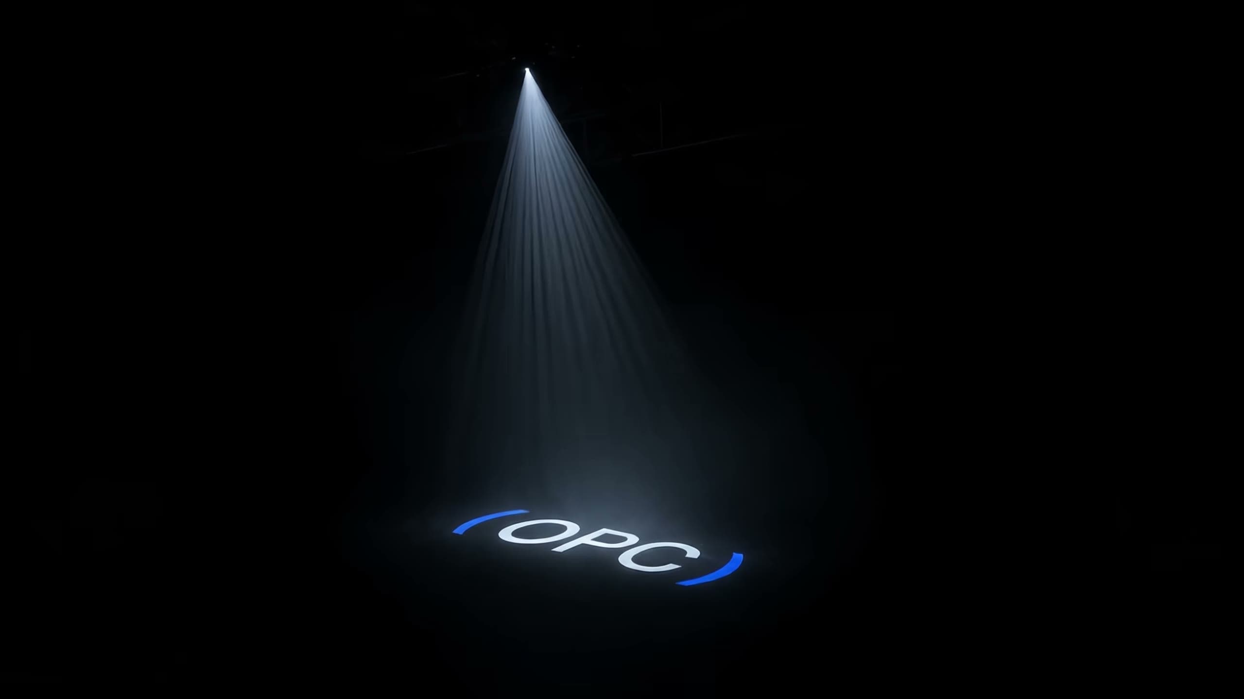 A single beam through haze throwing ( OPC ) on the floor of a black room, the brackets in cobalt.