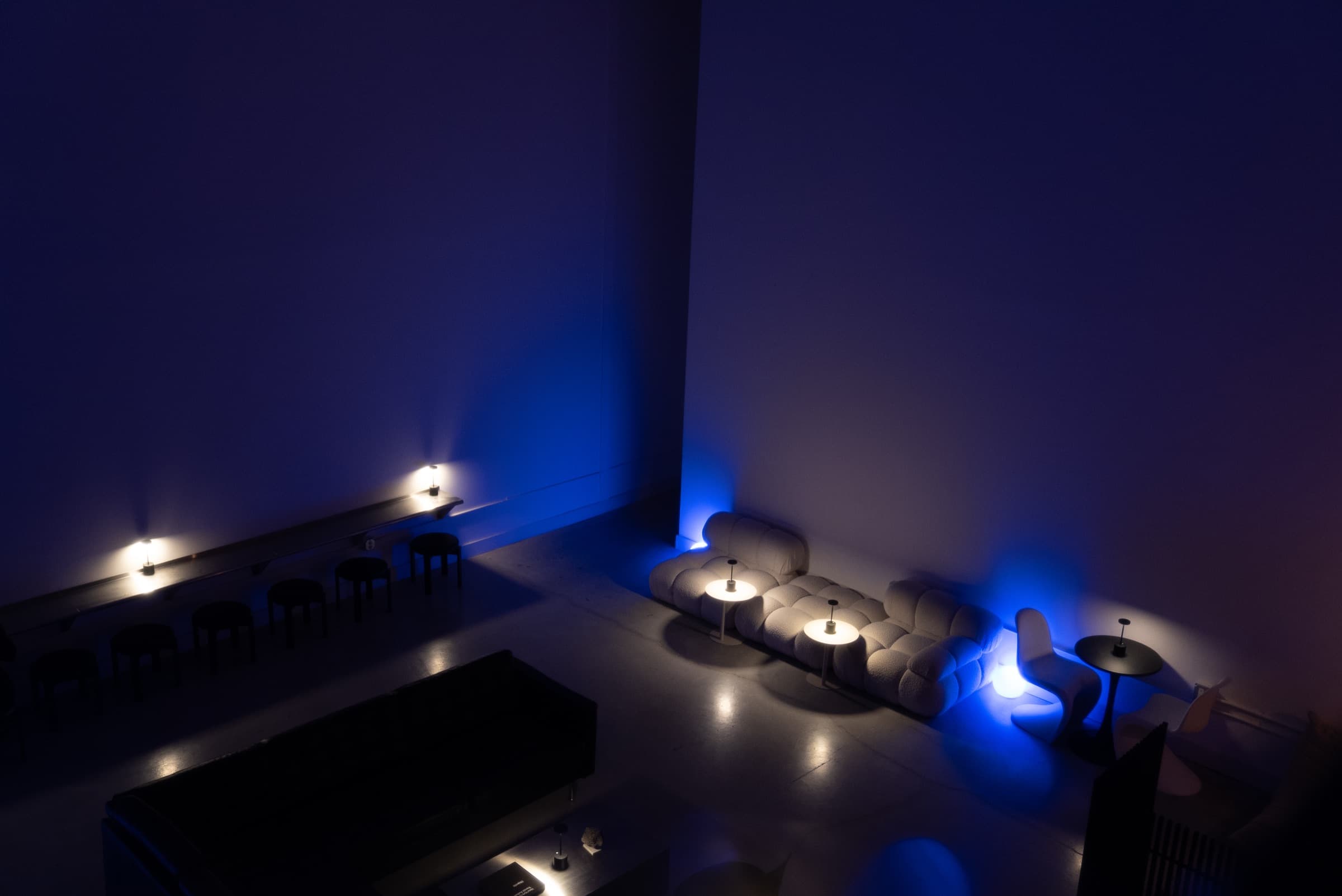 The Safehouse lounge from above, half in cobalt wash and half in warm lamplight.