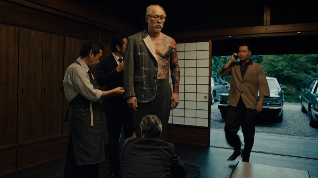 Scene 06: the tattooed oyabun being fitted as the messenger in a brown suit crosses the room.